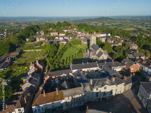 Shaftesbury historic town with Holy Trinity Church on top of the hill. Aerial panoramic view of the town and green English countryside on a sunny morning. Old houses with tile roofs. photo