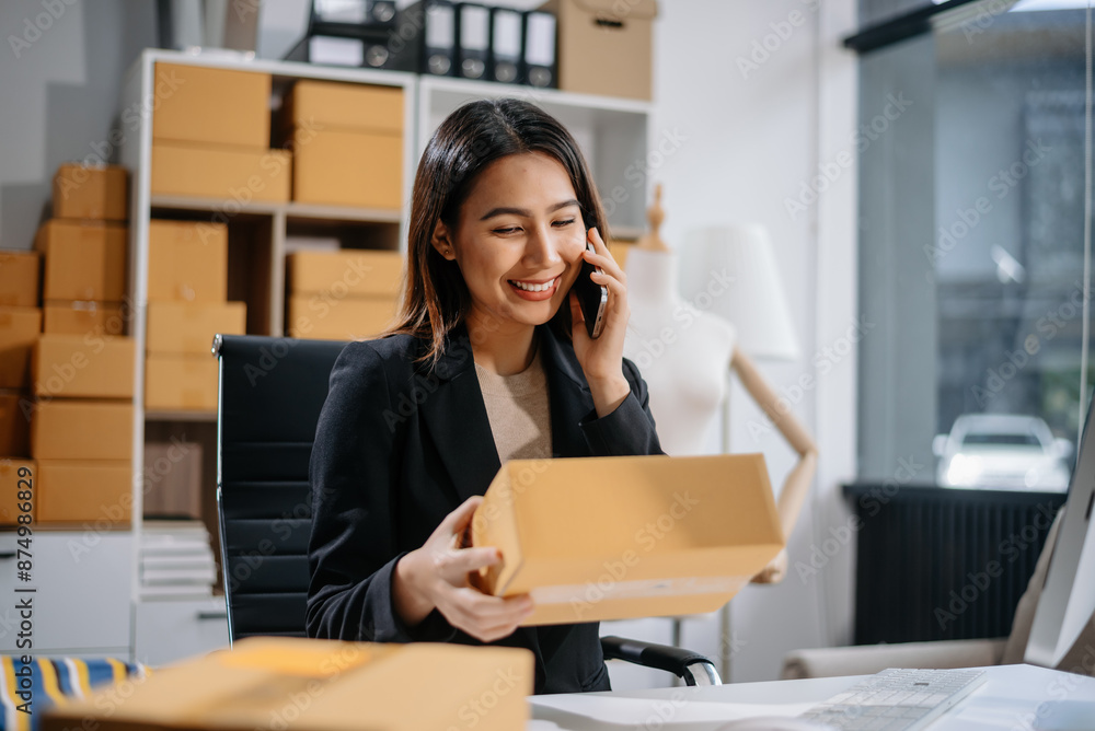 Asian woman prepares parcels and checks online orders on tablet and laptop for delivery online shopping and small business success Asian woman prepares parcels and checks online orders on tablet and laptop for delivery online shopping and small business success