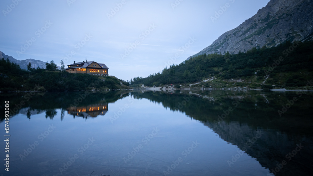 Mountain lodge with lights on located on a bank of lake during dusk, Europe, Slovakia Mountain lodge with lights on located on a bank of lake during dusk, Europe, Slovakia