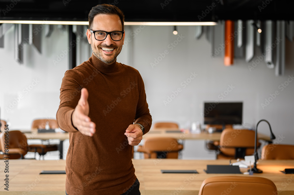 Portrait of confident businessman smiling and offering handshake while standing in meeting room Portrait of confident businessman smiling and offering handshake while standing in meeting room