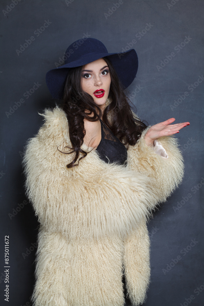 Surprised young brunette lady with makeup and long curly hair posing on blue background, fashion beauty studio portrait Surprised young brunette lady with makeup and long curly hair posing on blue background, fashion beauty studio portrait