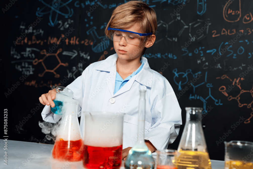 Tableau sur toile Blonde hair schoolboy in laboratory wear lab coat stand and learn science of chemistry technology in STEM class