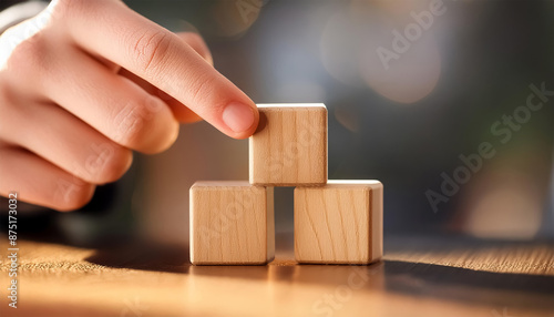 hand stacking three wooden cubes on top of each other