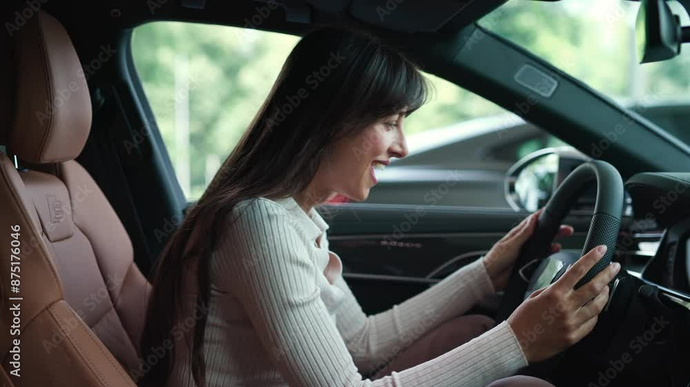 Side view of happy Caucasian woman enjoying test driving new automobile. Beautiful client happily observing equipment in car salon. Touching steering wheel with hands. Selecting best auto. Side view of happy Caucasian woman enjoying test driving new automobile. Beautiful client happily observing equipment in car salon. Touching steering wheel with hands. Selecting best auto.