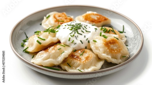 A plate of Polish pierogi with sour cream and chives on a white background.