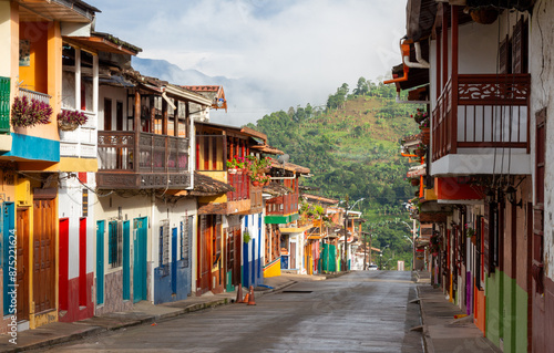 Street in Jardin, Jardín, Antioquia, Colombia. Green background, colorful colonial facades and houses. Clouds, blue sky.