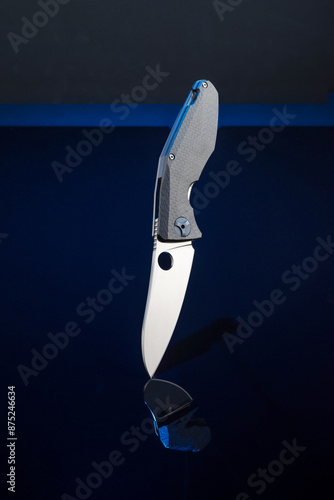 Premium quality folding pocket knife. The knife and its reflection. Knife on a black background. Brand knife. Vertical knife. photo