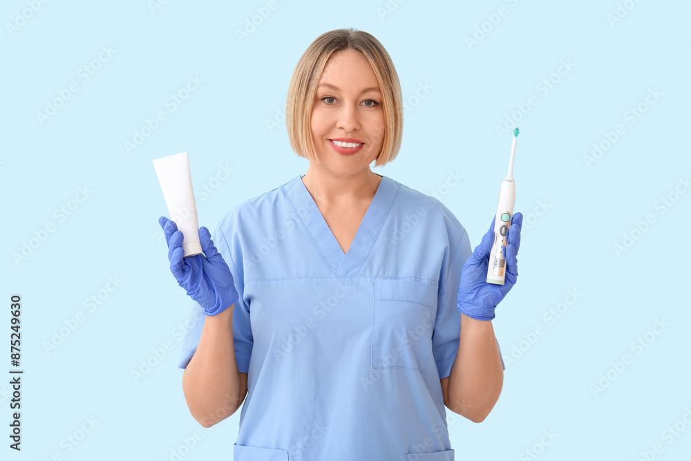 Female dentist with tooth brush and paste on blue background Female dentist with tooth brush and paste on blue background