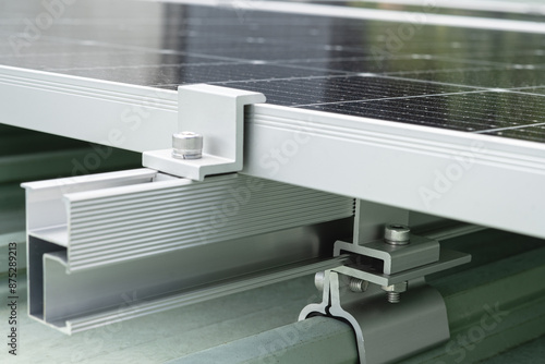 Close up of the clamps and rails holding the metal roof panels of the solar cell system.