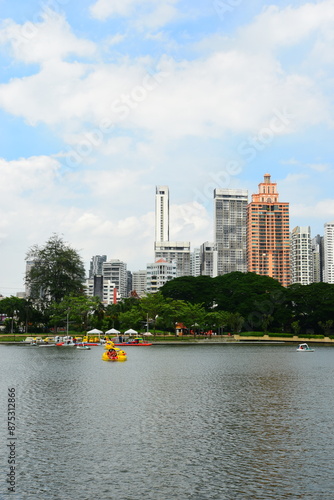 Bangkok, Thailand. July 6, 2024 : Cityscape view of Lake Ratchada situated in the Benjakitti Park with flowers, Benchakitti Forest Park is new landmark. On a hot, sunny morning during the wet season. photo