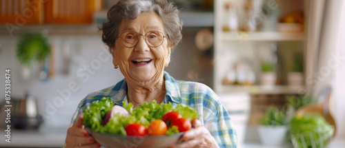 An elderly woman beams with joy as she holds a bowl of fresh vegetables in her kitchen, reflecting health, warmth, and homegrown pride.