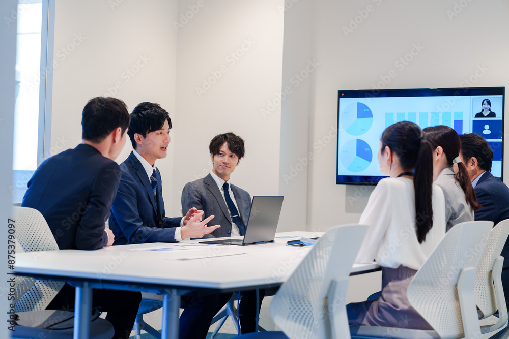 スーツを着て会議で話す若い男性