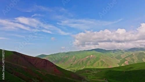 Wide open spaces with lush green hills and serene valleys under blue sky with white clouds, revealing tranquility and beauty of green jailoo pastures in Kyrgyzstan photo