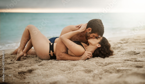 Couple, travel and kiss on beach for romance, summer and fun date adventure in love with bikini. Man, woman and intimate outdoor for holiday, happiness and commitment with hug, flare and connection