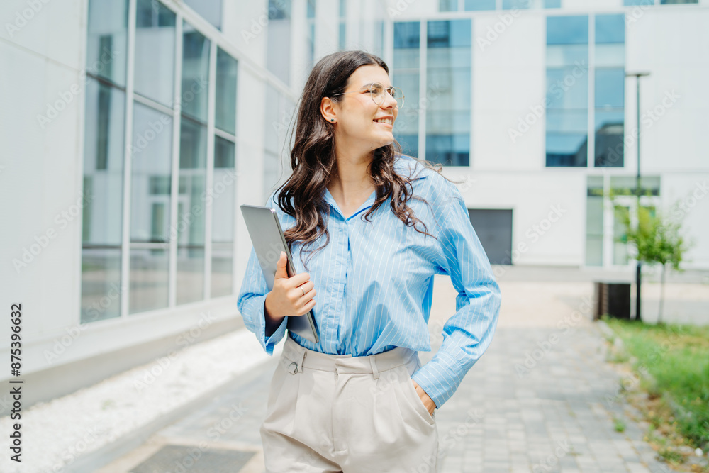 One beautiful young successful business woman going to work at business office modern building while holding laptop and wearing glasses One beautiful young successful business woman going to work at business office modern building while holding laptop and wearing glasses