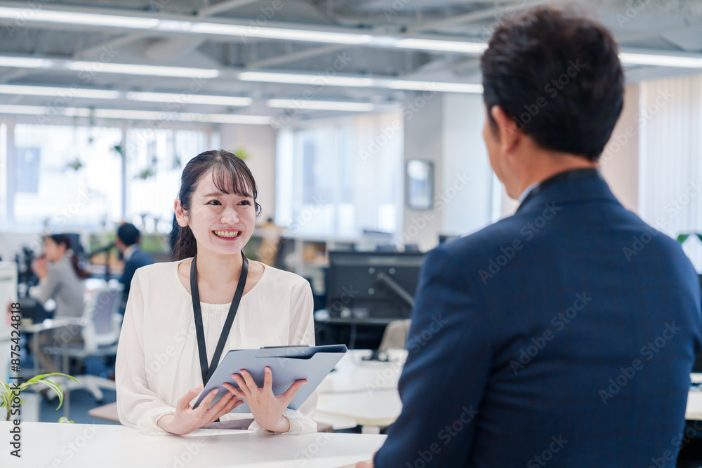 Obraz premium 窓口で来客の対応をする女性スタッフ