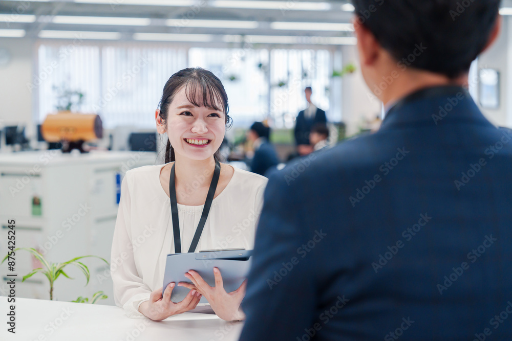 Obraz premium 窓口で来客の対応をする女性スタッフ