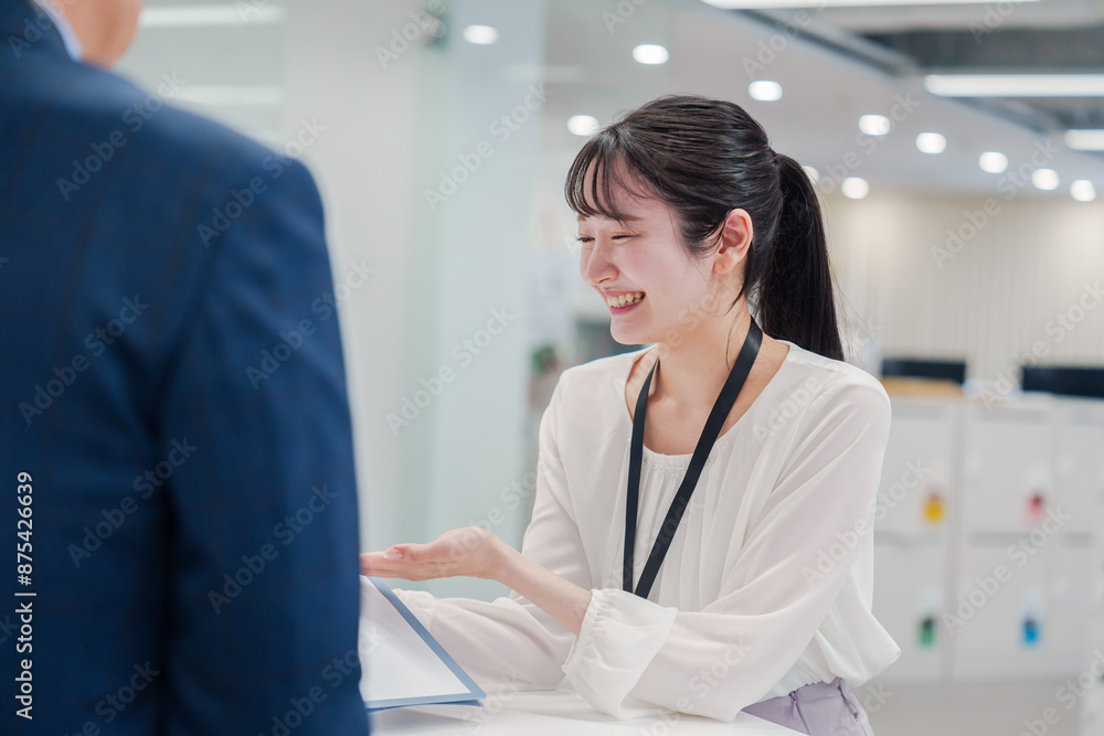 Obraz premium 窓口で来客の対応をする女性スタッフ
