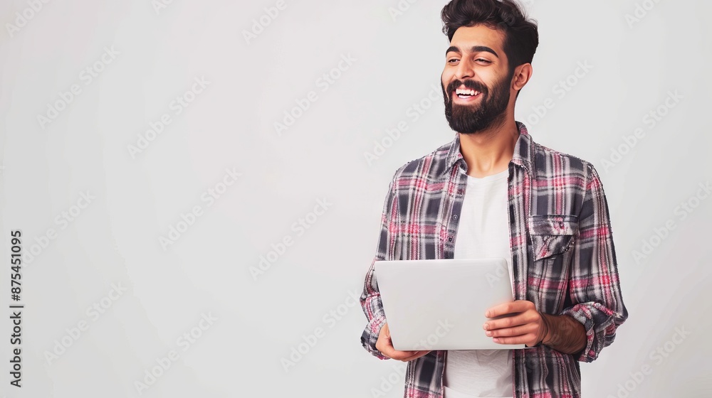 Cheerful arabian or indian young man with beard, wearing casual shirt, standing over isolated white background, holding laptop, looking to the side, smiling joyfully, dreaming, thinking Cheerful arabian or indian young man with beard, wearing casual shirt, standing over isolated white background, holding laptop, looking to the side, smiling joyfully, dreaming, thinking