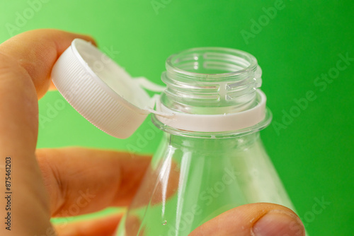 Plastic bottle with a new cap for mineral water. Concept. EU Directive on environmental protection, Green background, close up