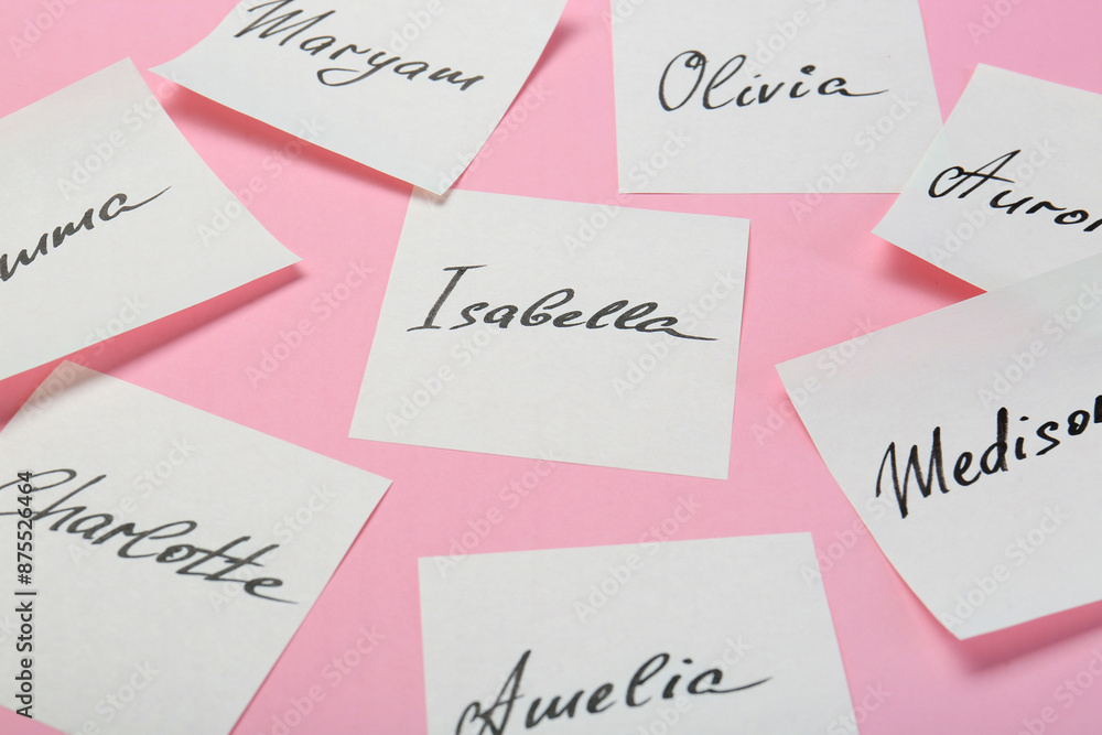 Paper stickers with different names on pink background, closeup. Choosing baby's name Paper stickers with different names on pink background, closeup. Choosing baby's name