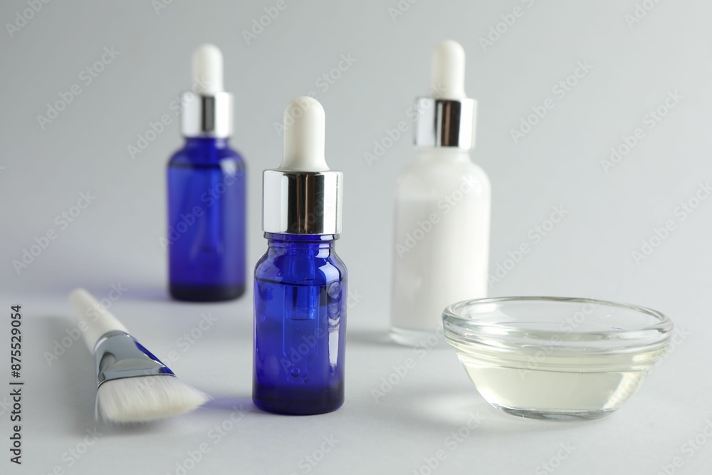 Bottles of chemical peel, bowl with liquid and brush on light background, closeup. Peeling procedure Bottles of chemical peel, bowl with liquid and brush on light background, closeup. Peeling procedure