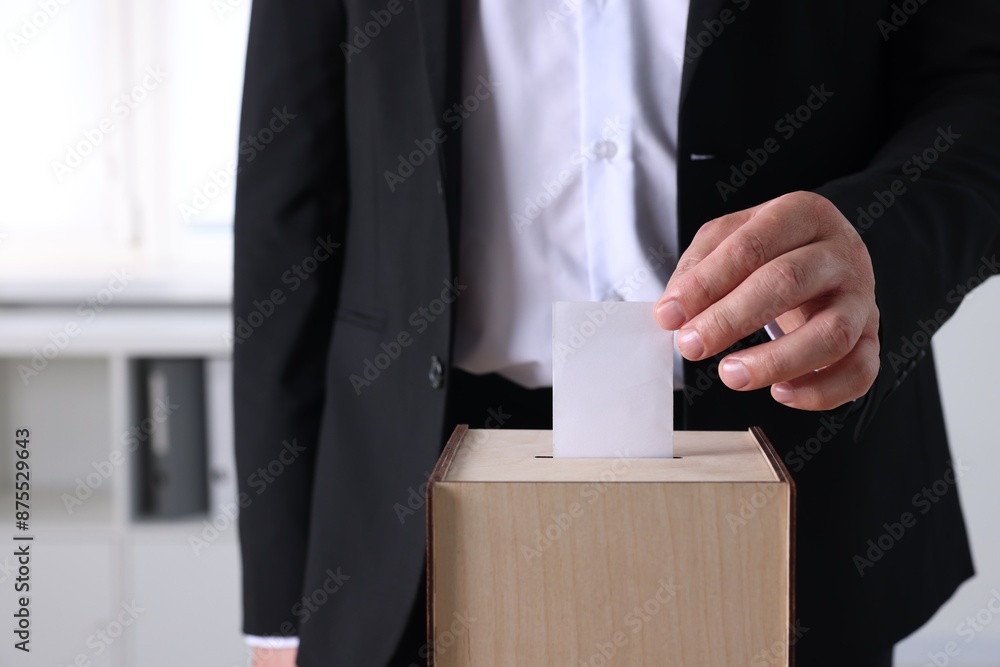 Man putting his vote into ballot box indoors, closeup Man putting his vote into ballot box indoors, closeup