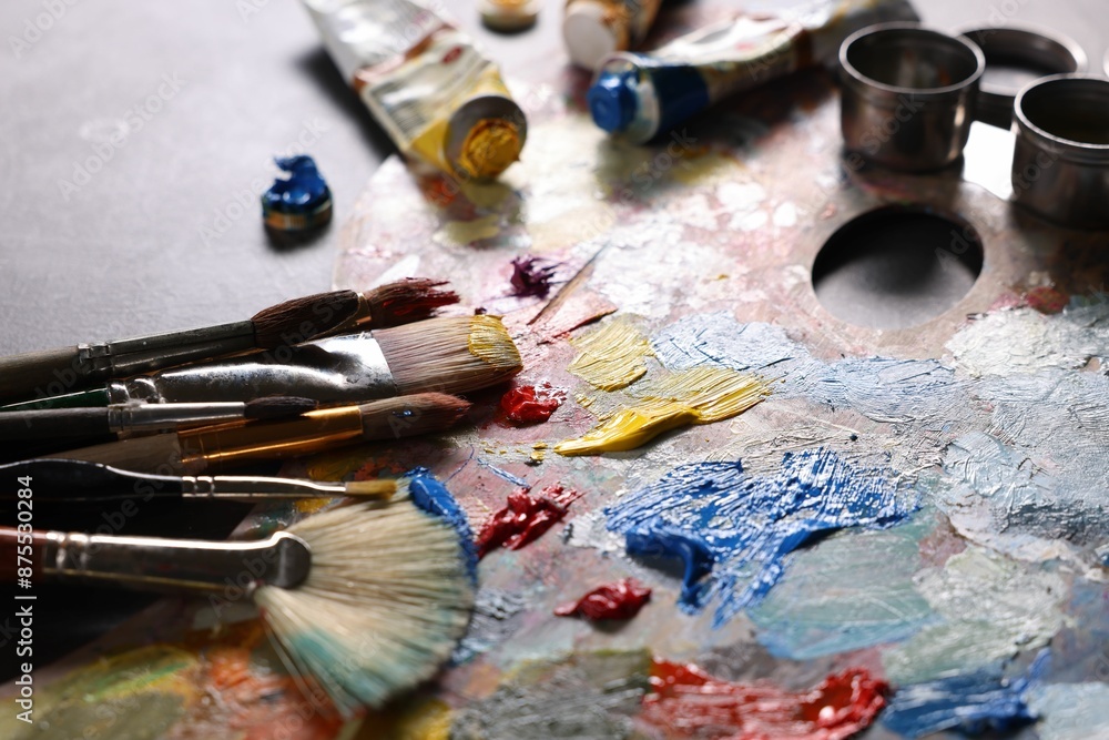 Obraz premium Artist's palette, brushes and paints on grey table, closeup
