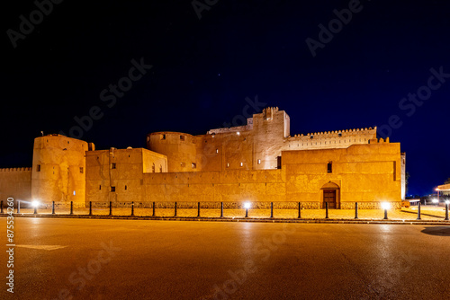 Jabreen citadel fortress stone walls and round bastion tower in night illumination, Bahla, sultanate Oman
