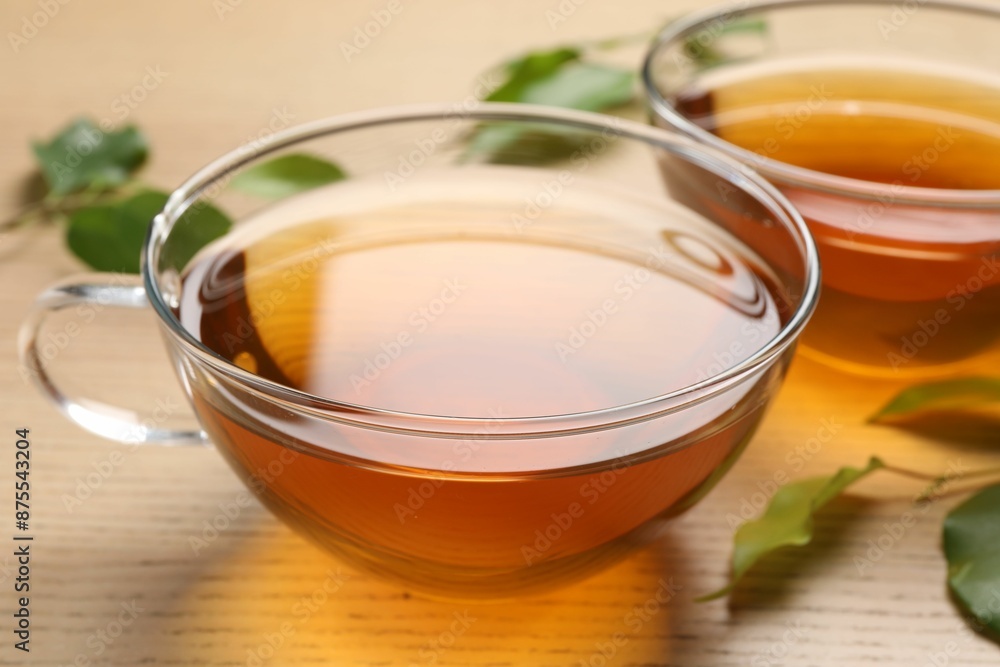 Refreshing green tea in cups and leaves on wooden table, closeup Refreshing green tea in cups and leaves on wooden table, closeup