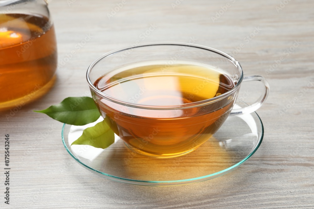 Refreshing green tea in cup and leaves on light wooden table, closeup Refreshing green tea in cup and leaves on light wooden table, closeup