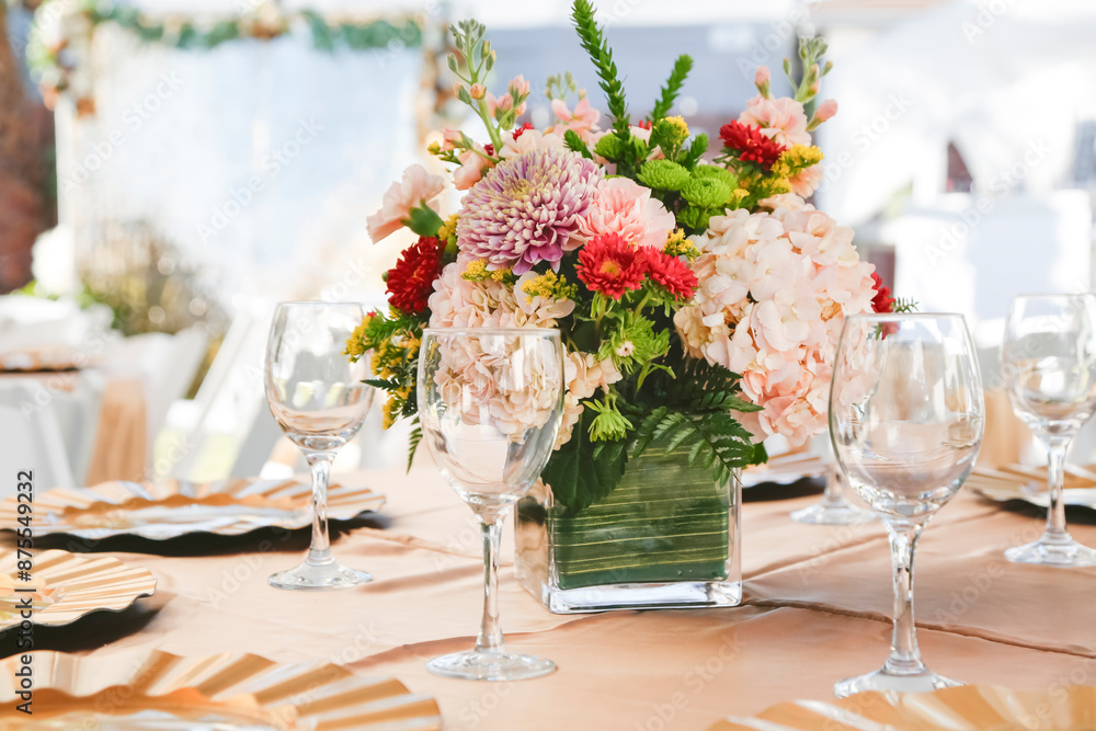 A view of a table setting at an event, featuring a beautiful flower bouquet. A view of a table setting at an event, featuring a beautiful flower bouquet.