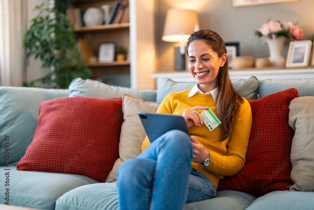 Happy satisfied woman paying with credit card while shopping online over tablet pc and relaxing on the couch at home. Happy satisfied woman paying with credit card while shopping online over tablet pc and relaxing on the couch at home.