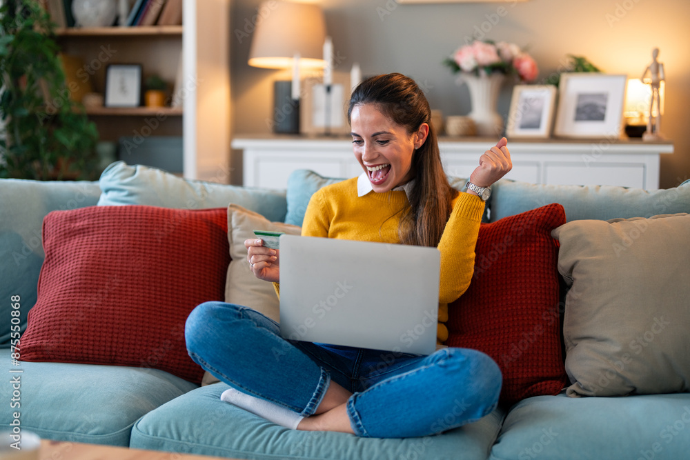 Businesswoman with credit card pumping fist and looking excited while doing online shopping on laptop. Businesswoman with credit card pumping fist and looking excited while doing online shopping on laptop.