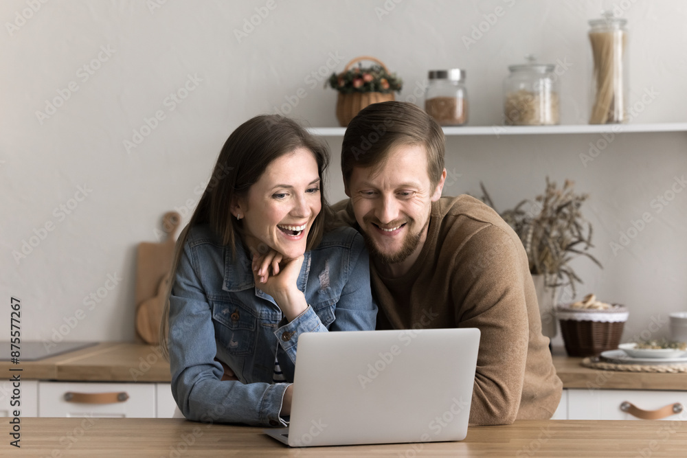 Happy millennial couple rest in kitchen with laptop, browse website, make purchase, read funny news, chat on social networks, websurfing information, spend time together on internet on weekend at home Happy millennial couple rest in kitchen with laptop, browse website, make purchase, read funny news, chat on social networks, websurfing information, spend time together on internet on weekend at home
