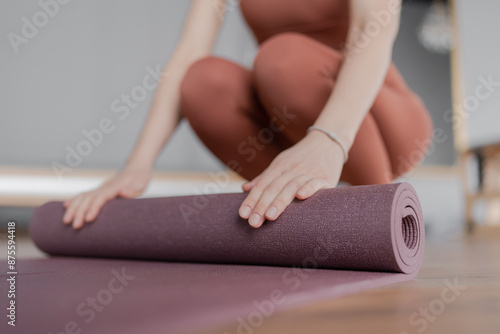 Woman trainer rolling out a mat after class. Rolled yoga mats in a studio create a peaceful atmosphere for meditation and exercise.