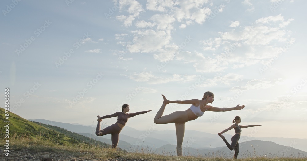 Fototapeta premium Women Practicing Yoga at Sunrise on Mountain in Slow Motion