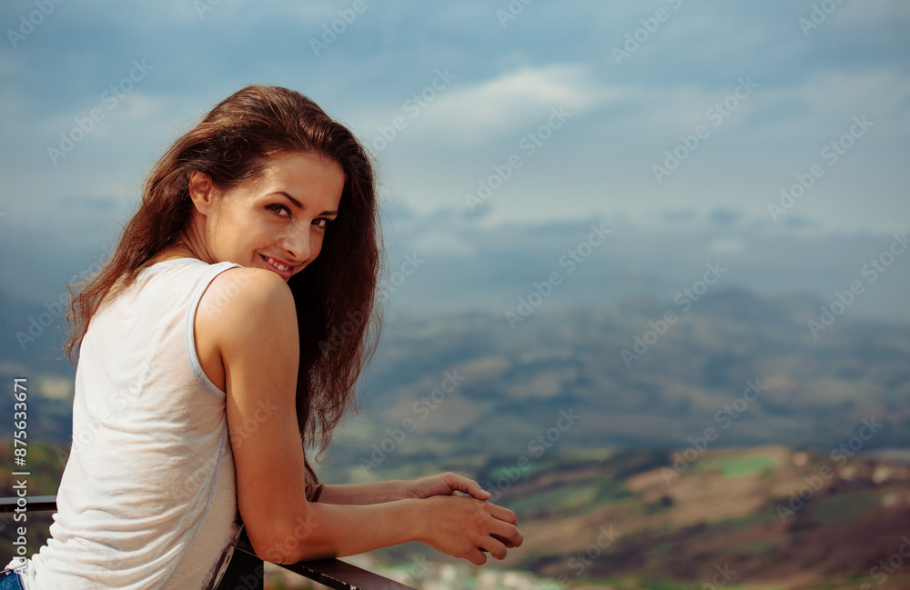Happy smiling brunette woman posong top view mountains blue sky background with long curly brown hair in summer sunny weather. Outdoor casual lifestile banner Happy smiling brunette woman posong top view mountains blue sky background with long curly brown hair in summer sunny weather. Outdoor casual lifestile banner