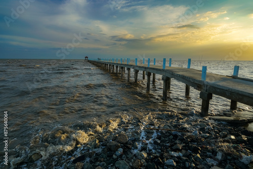 pier stretches into the sea at sunset, with a vibrant sky reflecting on the water