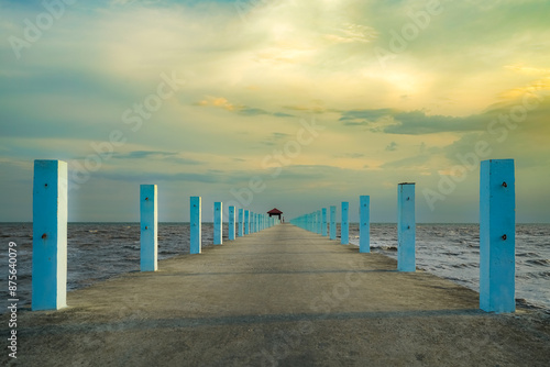pier stretching into the sea at sunset with a serene sky and clouds above the ocean