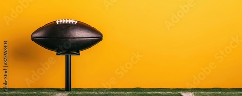 A football on a tee with a vibrant yellow background and green turf, ready for kickoff. Perfect for sports-related content.