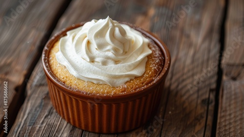 Vanilla cake topped with smooth milk cream in a ceramic dish on wood