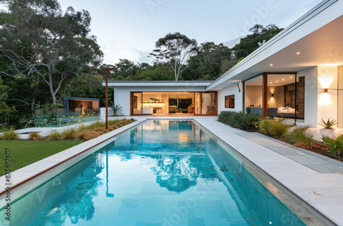 A modern home with an outdoor pool and a minimalist design, showcasing the sleek lines of white walls and flat roofs, complemented by lush greenery around it