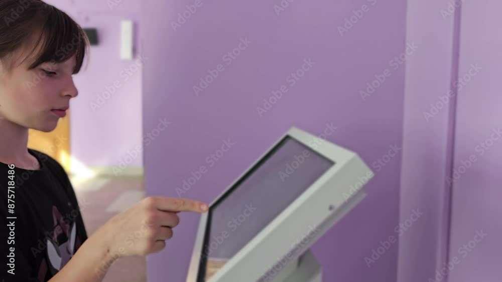 Young Person Using Touchscreen Kiosk in a Building Young Person Using Touchscreen Kiosk in a Building