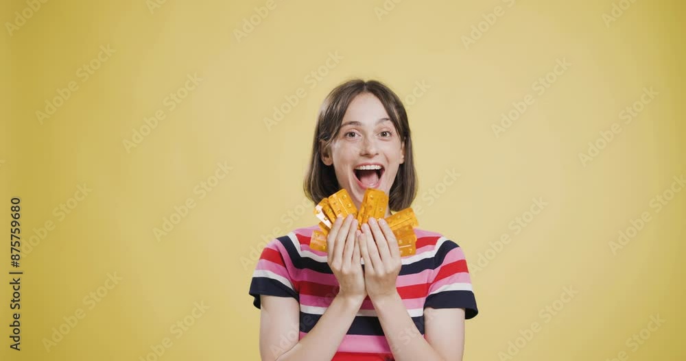 Young woman in striped shirt holding multiple orange pill cases against a yellow background Young woman in striped shirt holding multiple orange pill cases against a yellow background