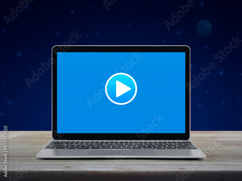 Play button on modern laptop computer moniyor screen on wooden table over fantasy night sky and moon, Business music online concept