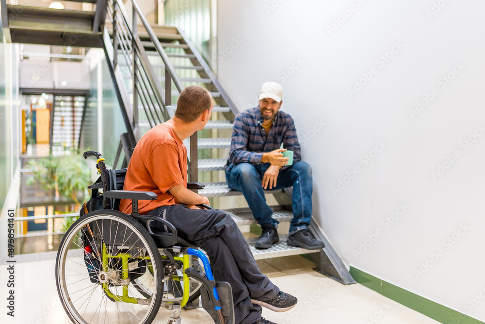 Man in wheelchair talking with a coworker during work break Man in wheelchair talking with a coworker during work break