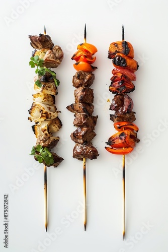 This image features three skewers with a variety of grilled meats and colorful vegetables displayed appealingly against a white background. photo