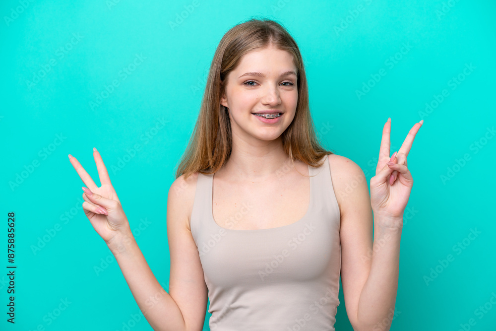 Teenager Russian girl isolated on blue background showing victory sign with both hands