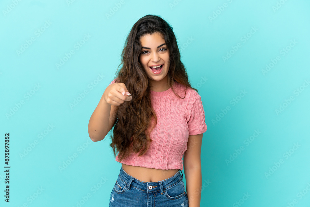 Young caucasian woman isolated on blue background surprised and pointing front Young caucasian woman isolated on blue background surprised and pointing front